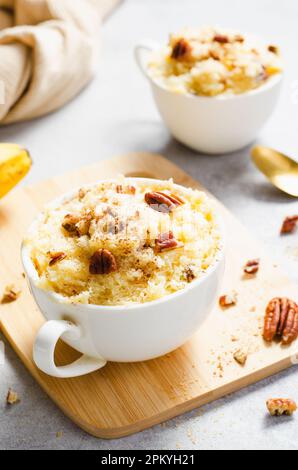 Bananenbecher Kuchen, hausgemachter Kuchen, in der Mikrowelle zubereitet und mit Pekannüssen dekoriert Stockfoto