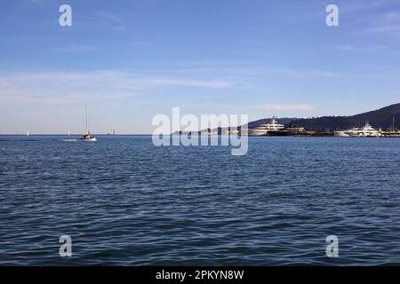 Das Meer und eine Klippe in einer Bucht, die man bei Sonnenuntergang aus der Ferne sieht Stockfoto