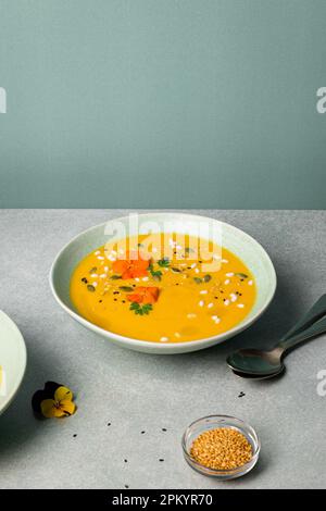 Leckere vegetarische Kürbiscremesuppe mit Kräutern und Sesamsamen, serviert in Schalen auf dem Tisch Stockfoto