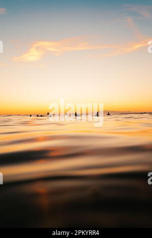 Malerischer Blick auf Touristen, die im Meer gegen Berge unter dem Himmel bei Sonnenuntergang schwimmen Stockfoto