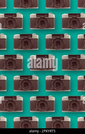 Hintergrund von verschiedenen, in Reihen angeordneten Oldtimer-Fotokameras auf blauer Oberfläche mit Objektiv Stockfoto