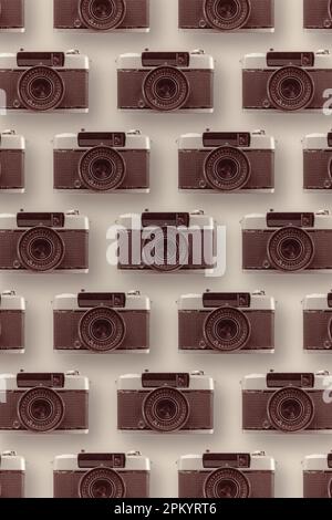Hintergrund von verschiedenen, in Reihen angeordneten Oldtimer-Fotokameras auf heller Oberfläche mit Objektiv Stockfoto