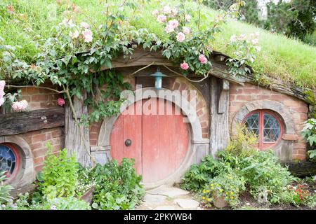 Das winzige Märchenhaus mit runder Tür und einem kleinen Garten mit Blumen (Neuseeland). Stockfoto