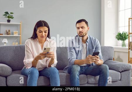 Ein eifersüchtiger Mann, der auf das Handy seiner Freundin spioniert Stockfoto