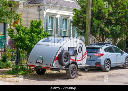 NEW ORLEANS, LA, USA - 4. APRIL 2023: Nucamp TAG Miniatur Wohnwagen Anhänger am geparkten Auto vor dem Wohnhaus in Uptown Stockfoto