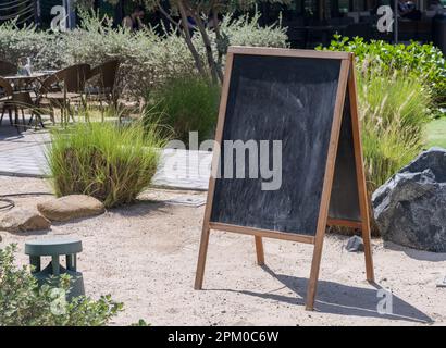 Hölzerne Tafel mit leerer Oberfläche, bereit für die Nachricht vor dem Café in Strandstadt Stockfoto