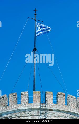 Foto der griechischen Nationalflagge, die im Wind auf dem Weißen Turm von Thessaloniki, Griechenland, weht Stockfoto