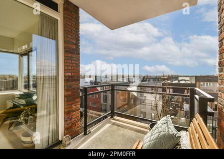 Ein Balkon mit Blick auf die Stadt von seinem Fenster aus, und es gibt einen leeren Stuhl auf dem Stockfoto