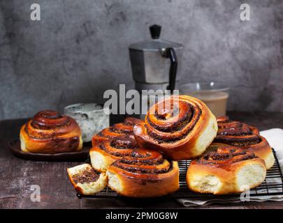 Hefeteig mit Zimt mit Mohnsamen, Rosinen und kandierten Früchten, serviert mit Kaffee. Rustikaler Stil. Stockfoto