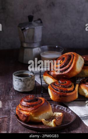 Hefeteig mit Zimt mit Mohnsamen, Rosinen und kandierten Früchten, serviert mit Kaffee. Rustikaler Stil. Stockfoto