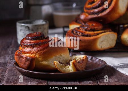 Hefeteig mit Zimt mit Mohnsamen, Rosinen und kandierten Früchten, serviert mit Kaffee. Rustikaler Stil. Stockfoto