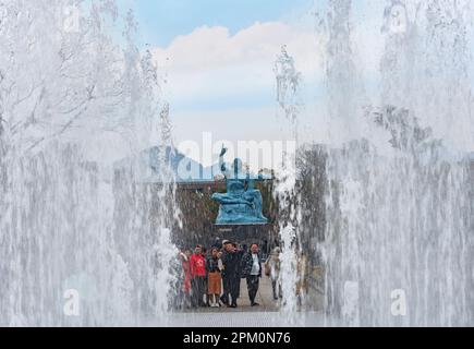 nagasaki, kyushu - 11 2022. dez.: Wasserstrahlen aus einem Brunnen umrahmen einen chinesischen Touristen an der Friedensstatue, die vom japanischen Bildhauer Seibo Kitam geschaffen wurde Stockfoto