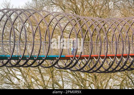 Oberhausen, NRW, 10. April 2023. Wanderer genießen einen meist sonnigen, milden Ostermontag auf der beliebten Brücke „Slinky Springs to Fame“ in Oberhausen. Die Fußgängerbrücke, die 406 Meter lang ist und den Rhein-Herne-Kanal durchquert, wurde vom Künstler Tobias Rehberger entworfen. Es wird nachts beleuchtet und soll vom verführerischen Spielzeug inspiriert worden sein. Kredit: Imageplotter/Alamy Live News Stockfoto