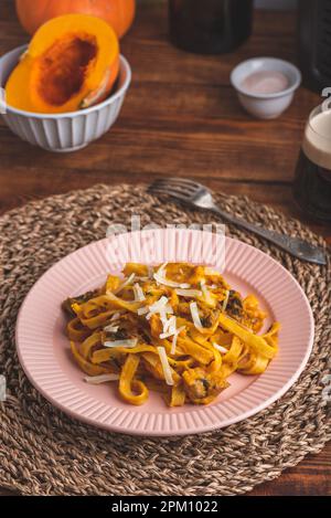 Fettuccine Pasta mit Kürbissauce und Pilzen garniert mit geriebenem Parmesan-Käse Stockfoto