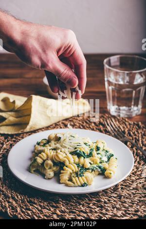 Fusilli Pasta mit Spinat und Ricotta garniert mit geriebenem Parmesan Käse auf weißem Teller Stockfoto