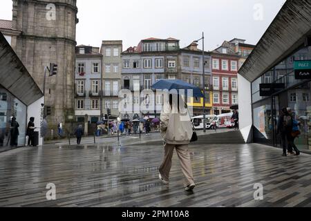 Porto, Portugal - 01.04.2023 Uhr: Regentag, Olivenbaumgarten (Jardim das Oliveiras), Touristen, die mit Sonnenschirmen in typischen Häusern im Hintergrund spazieren Stockfoto