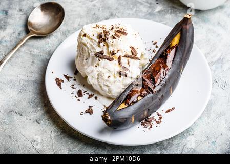 Süßes Dessert. Gegrillte Banane mit dunkler Schokolade, Zitronensaft und Vanilleeis. Stockfoto