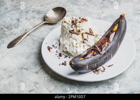Süßes Dessert. Gegrillte Banane mit dunkler Schokolade, Zitronensaft und Vanilleeis. Stockfoto