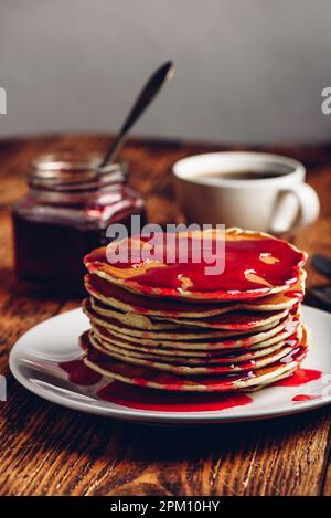 Stapel von amerikanischen Pfannkuchen mit roten Beeren Marmelade auf der Platte über rustikale Oberfläche Stockfoto