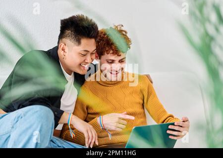 Ein Mann, der auf den Laptop-Bildschirm neben sein schwules Paar zeigt Stockfoto