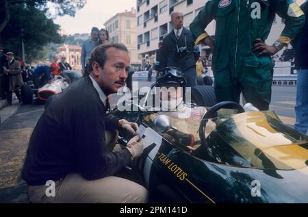 Formel 1: Ingenieur Colin Chapman spricht mit Fahrer Graham Hill (zweifacher Weltmeister) in Lotus vor dem Monaco Grand Prix in1967. Stockfoto