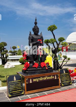 Eine majestätische schwarze Statue steht hoch vor dem Hintergrund eines klaren blauen Himmels. Die Statue befindet sich am Wat Arun Tempel in Bangkok, Thailand. Stockfoto