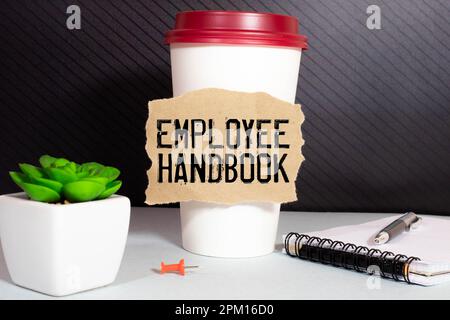 Geschäftskonzept. Auf einer weißen Oberfläche, einer Tasse Kaffee, einem Bleistift und einem Notizblock mit der Aufschrift – MITARBEITERHANDBUCH Stockfoto