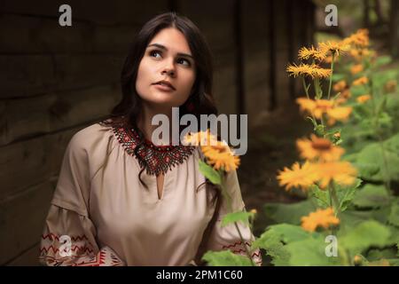 Eine schöne Frau, die ein gesticktes Kleid im blühenden Garten trägt. Ukrainische Nationalkleidung Stockfoto