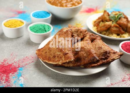 Traditionelles indisches Essen und Farbpulver auf grauem Tisch. Holi-Festival-Feier Stockfoto