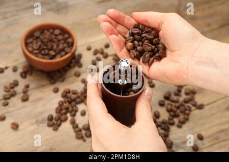 Frau mit manueller Kaffeemühle am Holztisch, Nahaufnahme Stockfoto