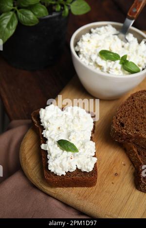 Brot mit Hüttenkäse und Basilikum auf dem Tisch Stockfoto