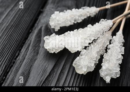 Stäbchen mit Zuckerkristallen auf schwarzem Holztisch, Nahaufnahme. Leckere Rock-Bonbons Stockfoto