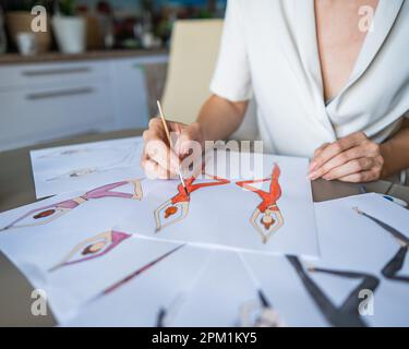 Eine gesichtslose Frau zeichnet Aquarelle von Sportbekleidung. Nahaufnahme der Hände eines Modedesigners. Stockfoto