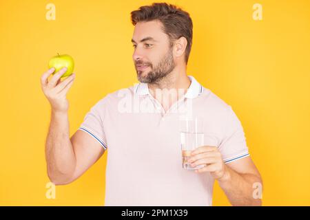 Ein Mann, der leckeren Apfel bastelt. Mann isst Apfel, Studioporträt. Frühstück am Morgen. Mann mit gesunden Zähnen, der Äpfel auf gelb isoliertem Hintergrund hält Stockfoto