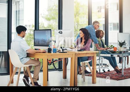 Alle Mann an Deck erledigen den Job. Gruppe kreativer Kollegen, die gemeinsam in ihrem Büro an einem Projekt arbeiten. Stockfoto