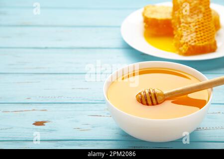 Schüssel mit Honig mit Wabenmuster auf blauem Holztisch. Draufsicht Stockfoto