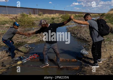 Juarez, Chihuahua, Mexiko. 10. April 2023. Mit dem Grenzzaun im Hintergrund überqueren Migranten einen kleinen Bach, während sie sich auf die Überquerung in die Vereinigten Staaten vorbereiten. Am Montag protestierten Hunderte venezolanischer Migranten vor der internationalen Brücke in Ciudad Juarez und überquerten dann die Grenze, um sich der Grenzpatrouille zu ergeben, mit der Absicht, humanitäres Asyl in den Vereinigten Staaten zu beantragen. (Kreditbild: © David Peinado/ZUMA Press Wire) NUR REDAKTIONELLE VERWENDUNG! Nicht für den kommerziellen GEBRAUCH! Kredit: ZUMA Press, Inc./Alamy Live News Stockfoto