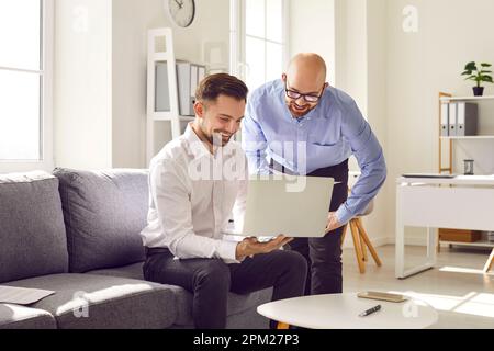 Zwei männliche Kollegen arbeiten mit einem Laptop im Büro zusammen Stockfoto