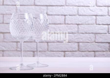 Zwei leere Weingläser auf einem Tisch vor einer Ziegelwand Stockfoto