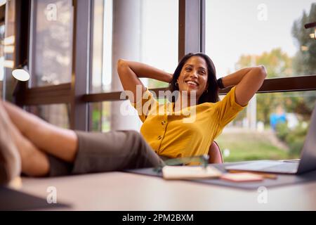 Reife Geschäftsfrau mit Füßen am Schreibtisch, die eine Pause im Büro macht Stockfoto