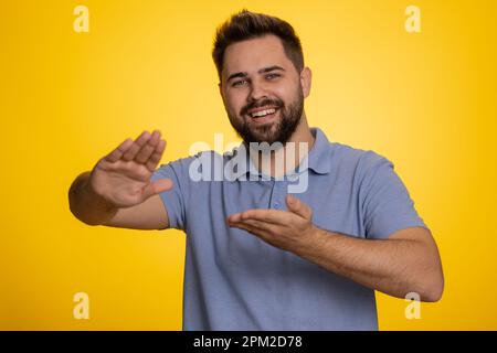 Ein junger Kaukasier, der Geld verschwendet, mehr Trinkgelder, großen Gewinn, Lotterie-Jackpot gewinnt, Erfolgreicher Einkauf, Bezahlung, Cashback. Ein Typ isoliert auf gelbem Studiohintergrund Stockfoto
