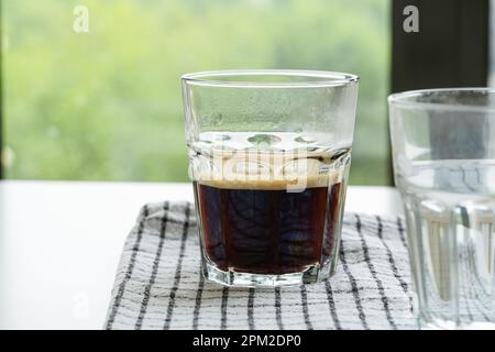 Frischer Espresso und Glas mit Wasser auf dem Tisch, Nahaufnahme Stockfoto