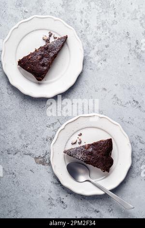 Scheiben Schokoladenkuchen mit Walnüssen, veganes Dessert auf grauem Hintergrund, direkt darüber Stockfoto