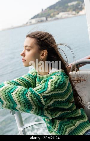 Seitenansicht einer jungen Frau in Strickpullover, die auf einer Yacht in der Türkei reist, Stockbild Stockfoto
