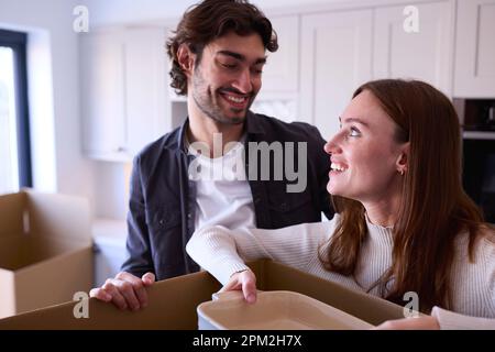 Ein Junges Paar, Das Nach New Home Zieht, Zusammen Kartons In Kitchen Auspacken Stockfoto