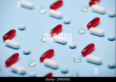 Makroaufnahme von medizinischen Pillen, Dragees und Kapseln im Muster auf isoliertem blauem Hintergrund. Pharmazeutische Industrie Stockfoto