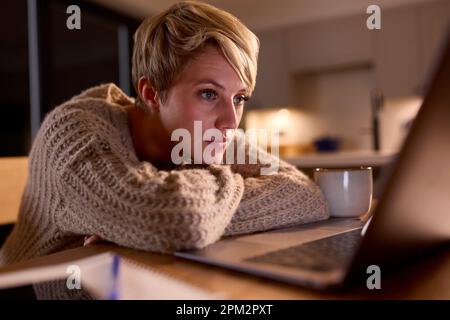 Junge Frau, Die Zu Hause Zu Hause Mit Einem Notebook Arbeitet Oder Studiert Und Auf Den Bildschirm Starrt Stockfoto