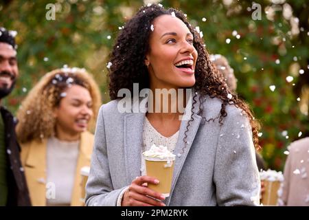 Eine Gruppe Von Freunden, Die Mäntel Tragen Und Draußen In Snow Stehen Und Heiße Schokoladengetränke Zum Mitnehmen Anbieten Stockfoto