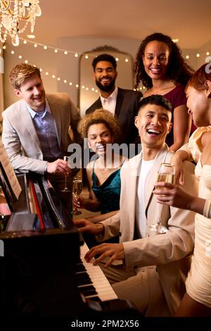 Gruppe Von Freunden Um Das Klavier, Die Weihnachten Oder Silvesterparty Gemeinsam Feiern Stockfoto