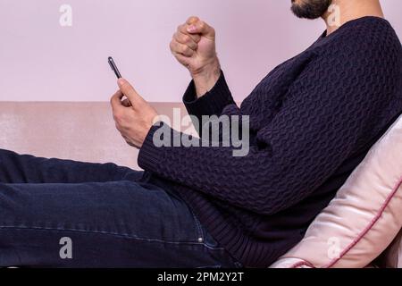 Glücklicher Mann, der auf sein Handy schaut. Ein weißer Mann erhält eine gute Nachricht Stockfoto